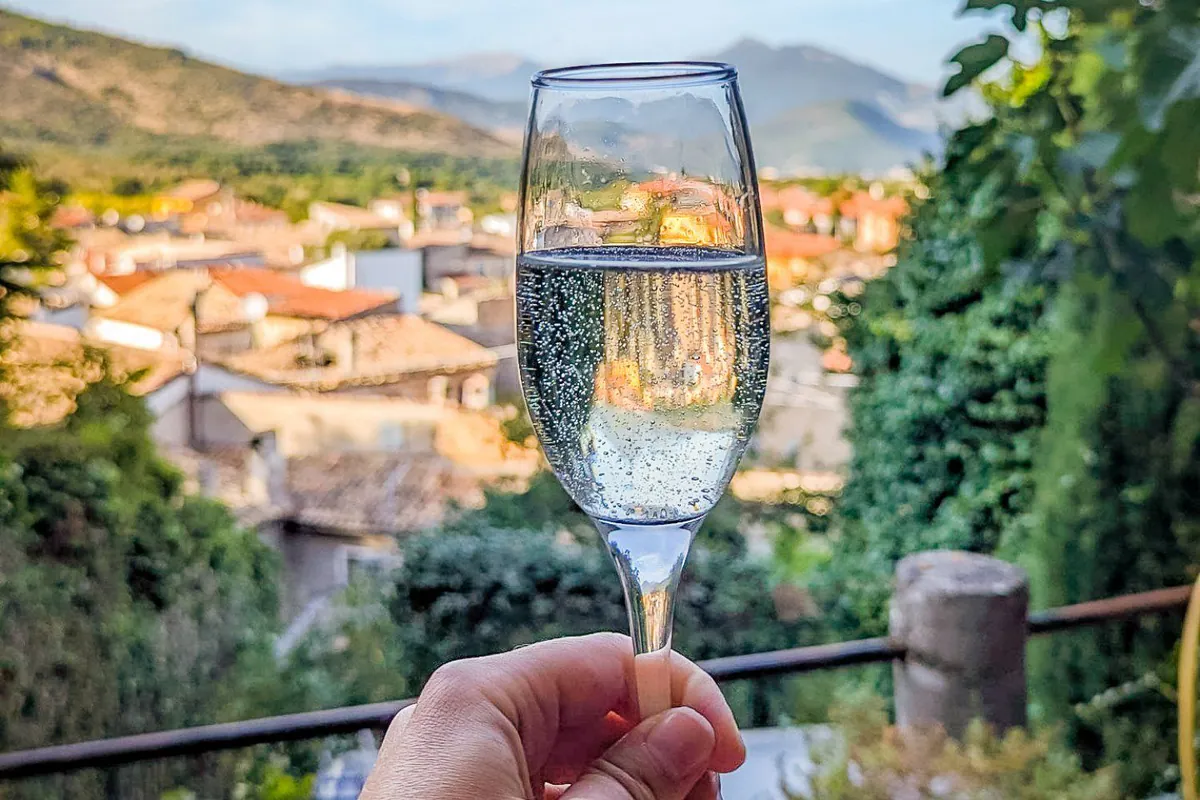 Ein Glas Prosecco vor den Dächern des Dorfs