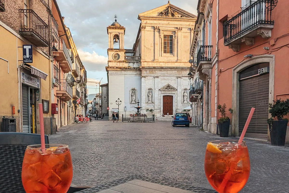 Zwei Gläser Aperol auf dem Tisch, dahinter die Kirche am Marktplatz