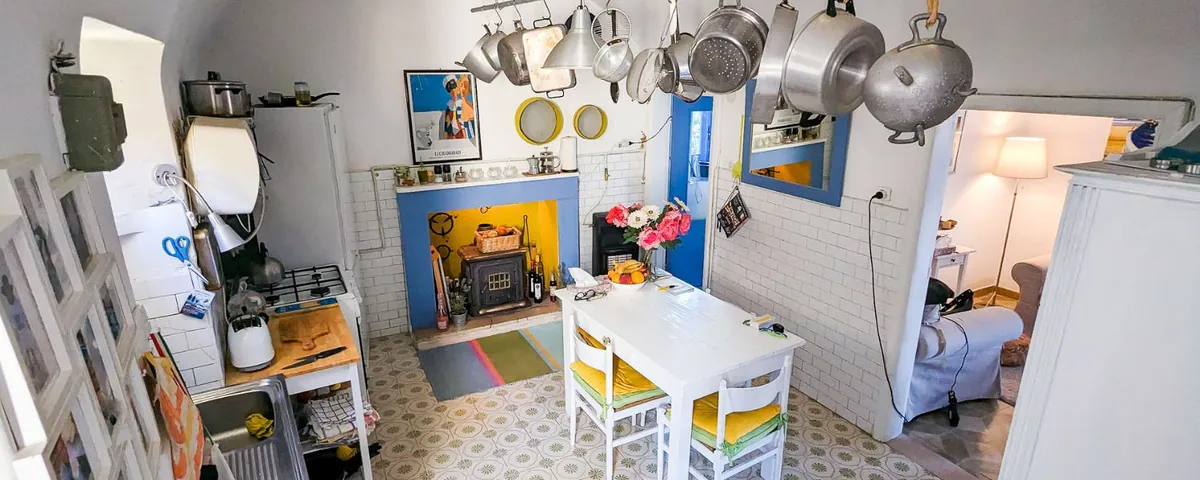 Blick in die Küche des Hauses, über dem Tisch hängen Töpfe und Pfannen