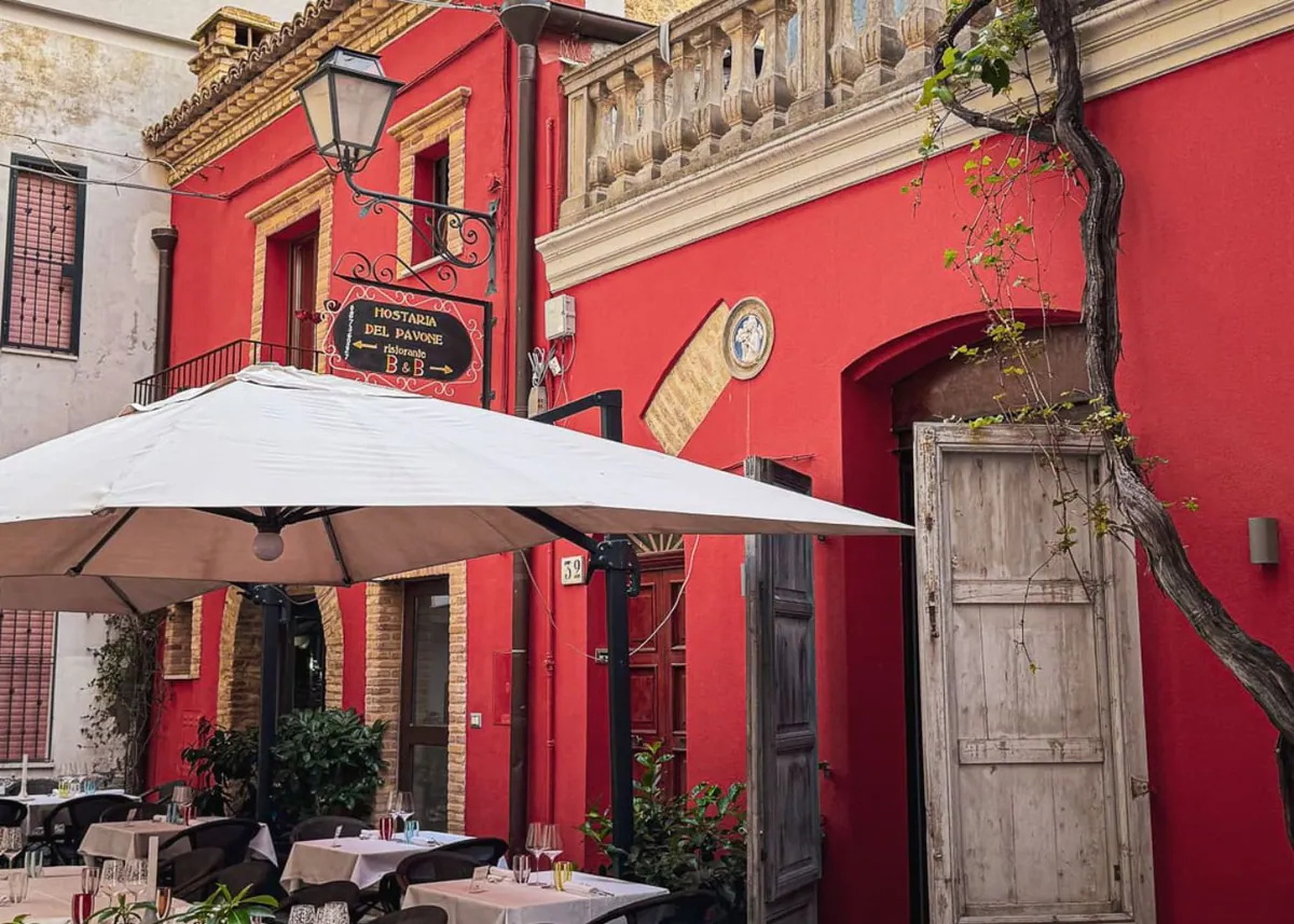 Rote Hausfassade mit Café-Tischen in der Altstadt von Vasto