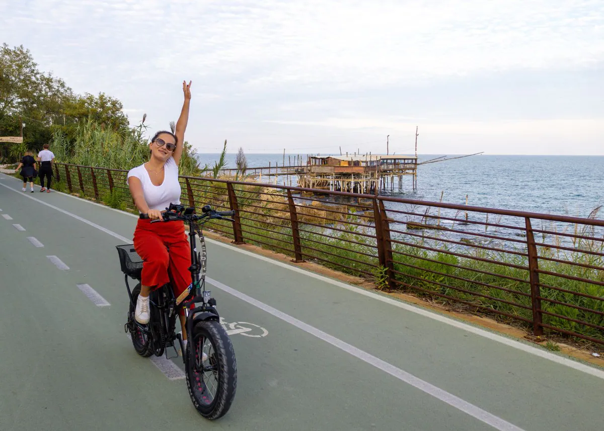 Radfahrerin auf dem Radweg an der Trabocchi-Küste, dahinter ein Trabocco