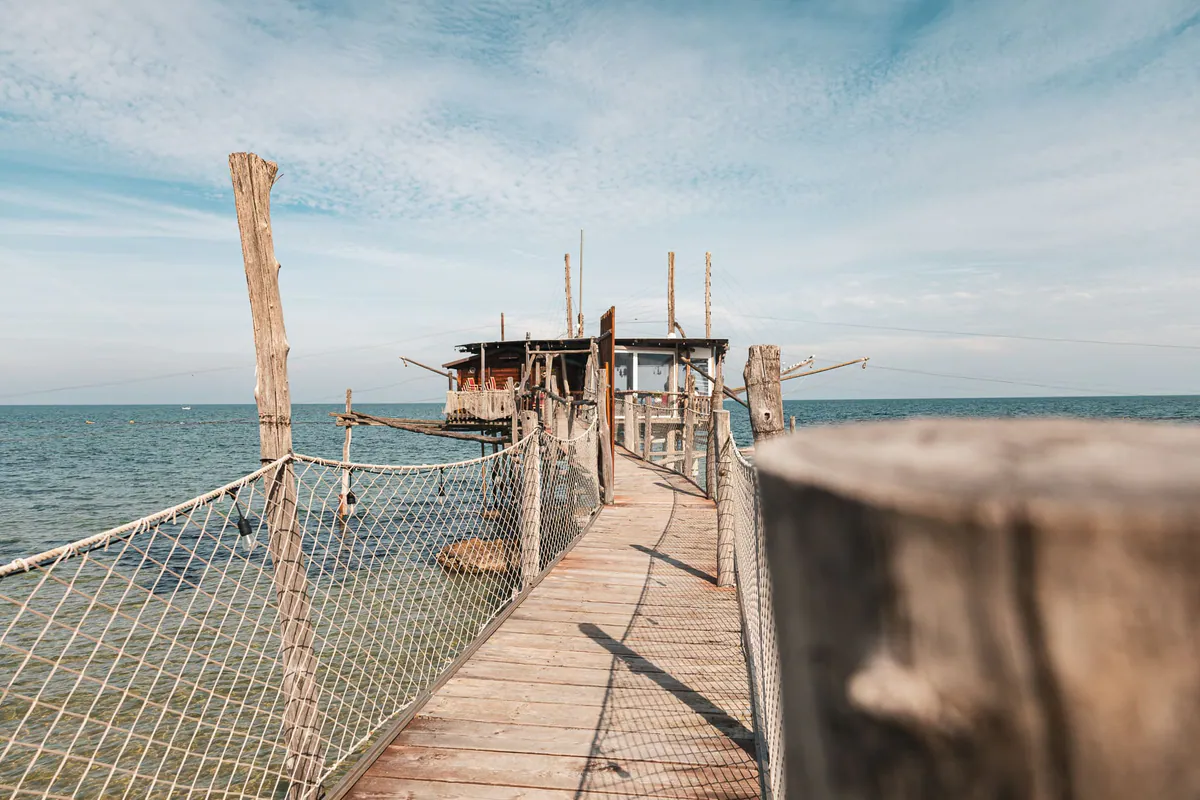 Ein hölzerner Steg führt über das Meer zu einem Trabocco