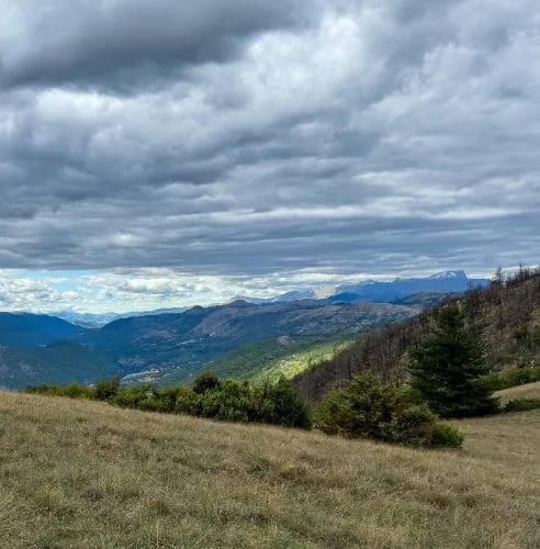 Grüne Hügel und Bergketten unter Wolken